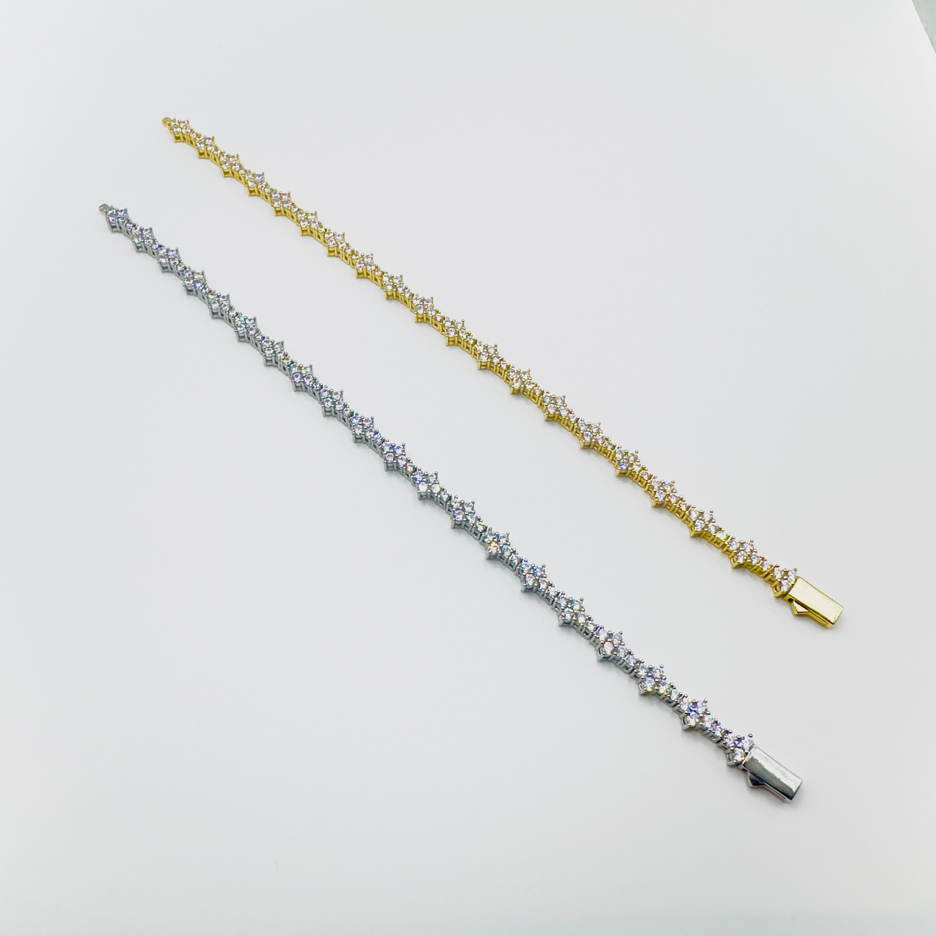 Two bracelets, one silver and one gold, on a light gray background