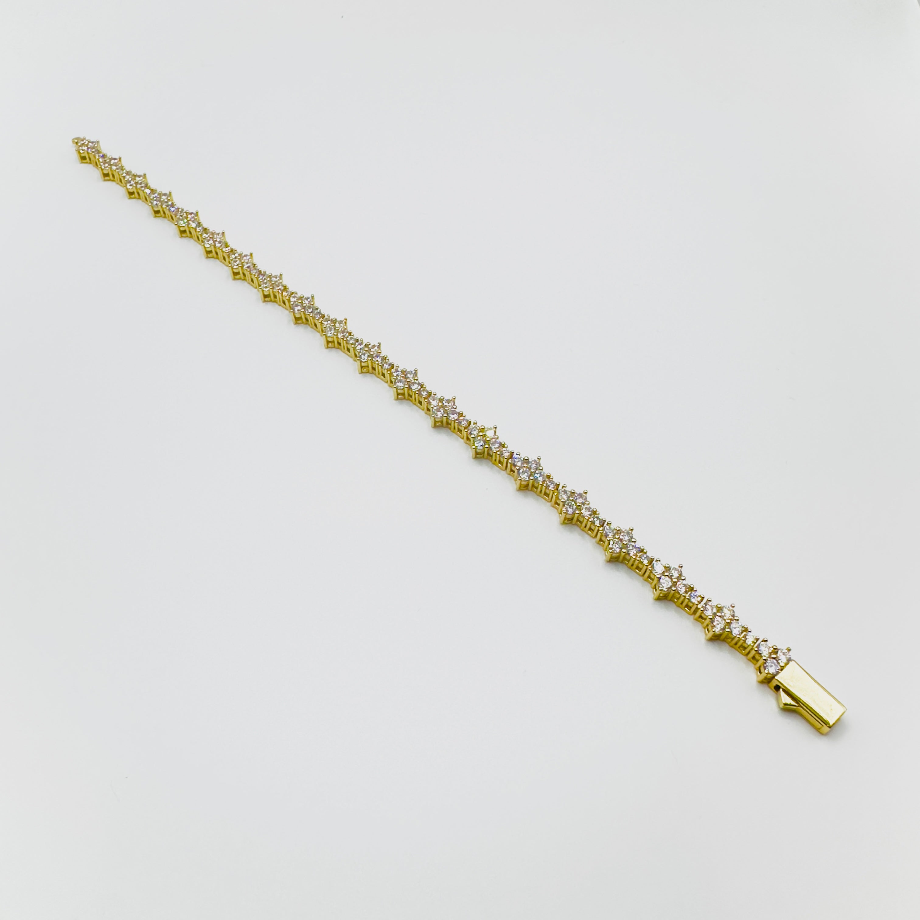 Gold bracelet with small diamonds on a light gray background